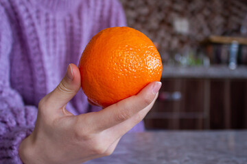 Closeup photo of woman holding orange in her hand.