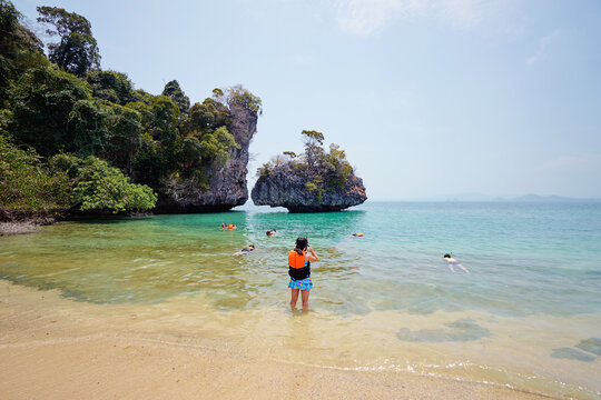 Safety First. A Group Of People Swimming On The Beach In Swimming Vests.