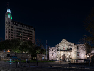 Side View of the San Antonio alamo at Night with Cannon and LArge Building on the background