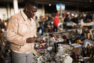 African American man chooses antiques on the flea market