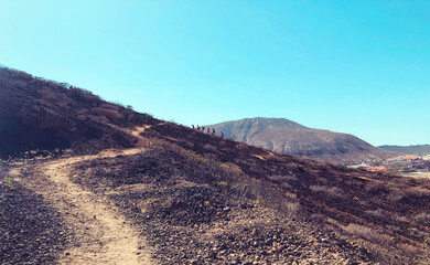 view of hiking desert trail with hikers away over mountain background