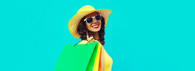 Portrait of beautiful happy smiling young woman with shopping bags wearing summer straw round hat...