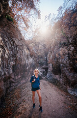 Naklejka premium Active lifestyle. Trekking and hiking. Young woman with rucksack in the rocks forest.