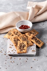Homemade crackers with tomato sauce on light background