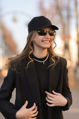 Portrait of a young beautiful blonde girl in a dark baseball cap.