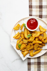 Overhead view of potatoes wedges and ketchup in bowl on plate