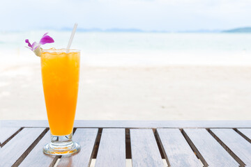 Orange juice with orchid flower on the beach background
