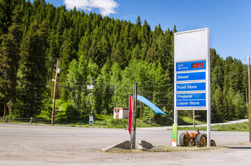 Gas station sign along a mountain road on a sunny summer day. Rising gas prices.