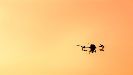 Silhouette drone flying on sunset.