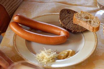 Vienna sausages with mustard, horseradish, and bread on a plate.