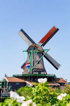 Colorful old windmill with Ducth flag in Zaanse Schans Village in Zaanstad North Holland The Neteherlands