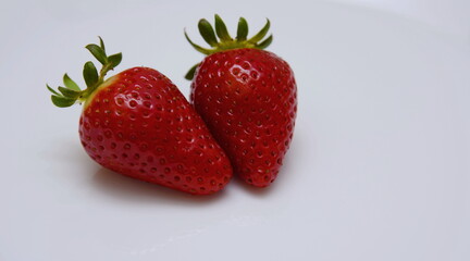 Two of freshly ripened strawberries on a white background. Perfectly beautiful strawberries close-up