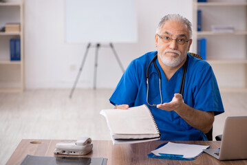 Old male doctor working in the clinic