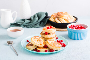 Ready-to-eat pancakes and cranberries on a plate and pan with pancakes on the table. Homemade breakfast dessert