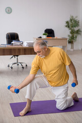 Old businessman employee doing sport exercises in the office