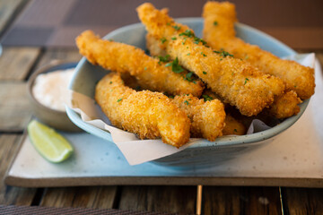 Fresh fried Brazilian tilapia fish strips with lime and tartar sauce known as isca de peixe. Traditional Brazilian appetizer. Selective focus