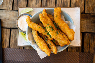 Fresh fried Brazilian tilapia fish strips with lime and tartar sauce known as isca de peixe....