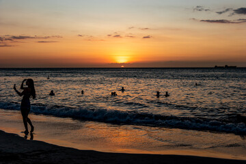 Fototapeta na wymiar Women at sunset on the beach taking with cellphone