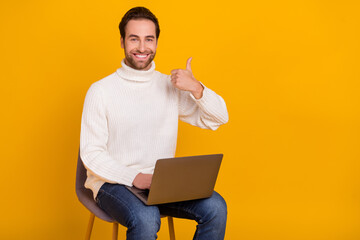 Photo of reliable remote employee sit chair hold laptop raise thumb up wear white sweater isolated yellow color background