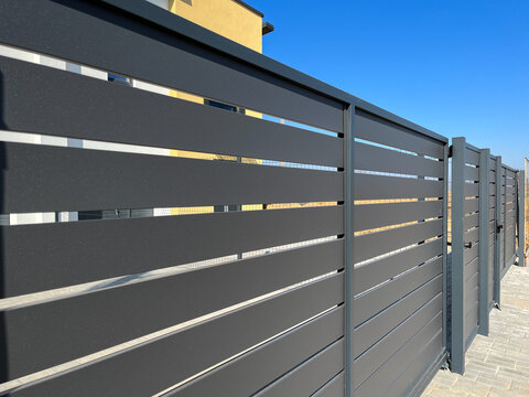 Modern metal fence for fencing the yard area. Horizontal sections of the fence made of metal