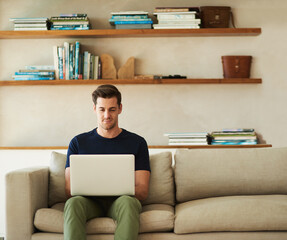 Weekends are made for wifi. Shot of a handsome young man using his laptop while sitting on the sofa at home.