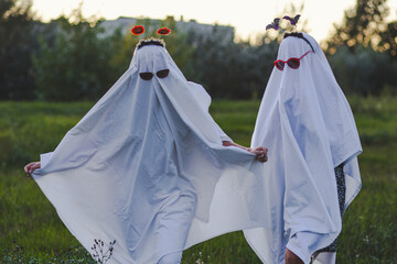 two people dressed up like funny ghosts in sunglasses running in field