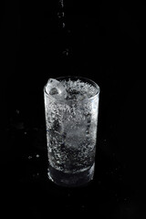 Soda water was flowing into a clear glass with ice.