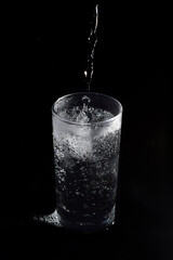 Soda water was flowing into a clear glass with ice.