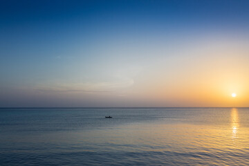 Obraz premium Boat at picturesque sunset. Aerial ambient seascape. Peaceful seascape with sailing boat and copy space. Colorful evening sky over tranquil ocean. Golden sunset at the beach. Tropical vacations. 