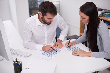 Setting up their monthly schedule. Shot of two young business colleagues discussing documents in the office.