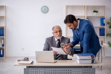 Obraz premium Old male boss and young male employee working in the office