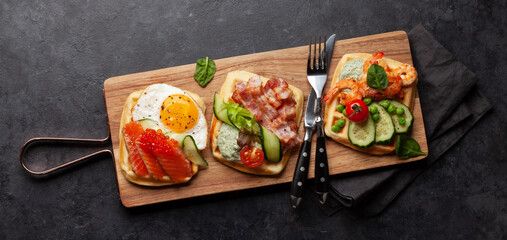 Breakfast waffles with fried eggs, salmon, cucumber and prawns