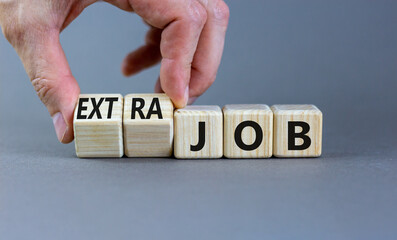 Extra job symbol. Businessman turns wooden cubes and changes concept words Job to Extra job. Beautiful grey table grey background, copy space. Business extra job concept.