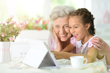 Cute little girl with her grandmother with tablet