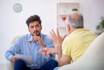 Obraz premium Old man visiting young male psychotherapist