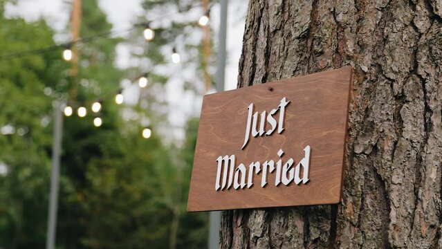 The inscription "newlyweds" is fixed on a tree in the celebration and ceremony area. Smooth camera movement