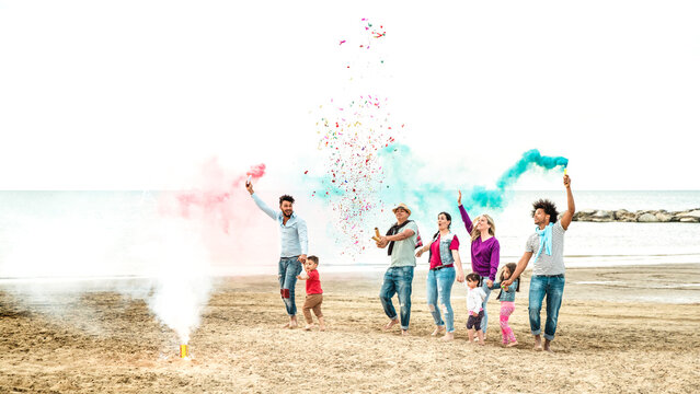 Young happy families having fun at beach on party mood with confetti and sparklers - Life style joy concept with mixed age people enjoying spring break moment - Horizontal crop with bright filter