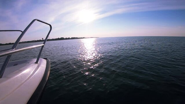 Seascape, view of sea waves with sun reflection from prow of motorboat. Boat jumping on waves on sunny summer day. Yacht motor boat sailing fast at sea horizon. Extreme sport entertainment background