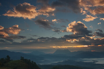 Glowing orange cloud on morning blue sky over a foggy valley and  mountain 