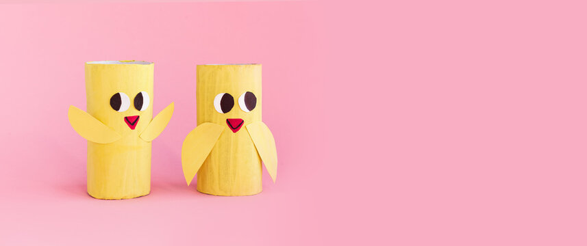 Holiday easy DIY craft idea for kids. Toilet paper roll tube toy's cute chick on pink background banner. Creative Easter, Christmas decoration eco-friendly, reuse, recycle handmade minimal concept