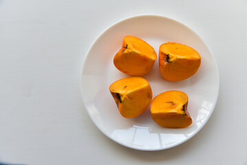 Delicious persimmon fruits on a white plate