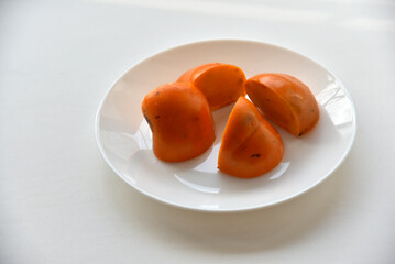 Delicious persimmon fruits on a white plate