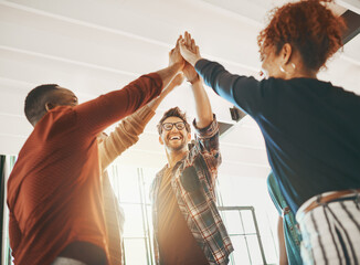 Collaborate then innovate. Shot of creative employees giving each other a high-five in the office.