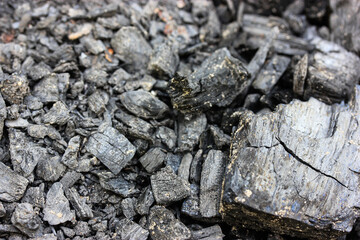 Black grey ash, black charcoal abstract background texture selective focus. Wood after burning in fire. Fertilizer for plants, ground. Black charcoal background. Coal texture top view. Green energy.