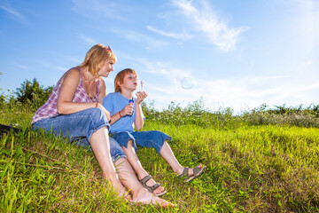 Fototapeta premium mother and son blowing bubbles outdoors