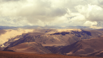 Thick white clouds hung over the Caucasian mountain valley, and the rays of the sun breaking through them illuminate the mountains.