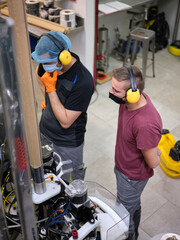Workers with mask controlling the machinery of a craft beer canning factory