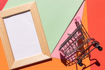 advertisement banner, promotion inscription. A wooden frame and shopping cart on a bright colorful background, a blank for the design, concept.Photo frame mock up with space for text
