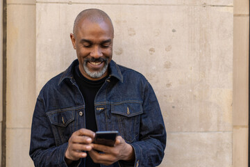 Mature black man in city using cell phone