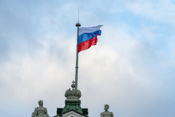 Russian national flag flutters in the wind against cloudy sky in the morning. Close-up view. Travel in Russia theme.